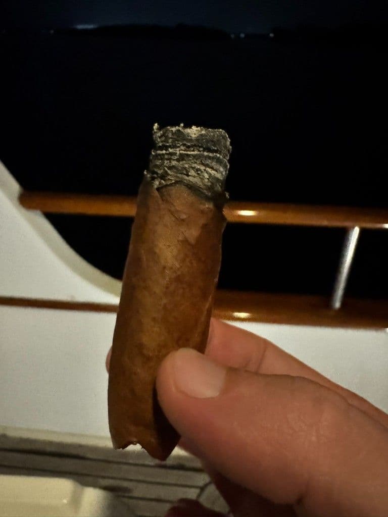 Patoro XO lit at night with dusty wrapper and jagged burn