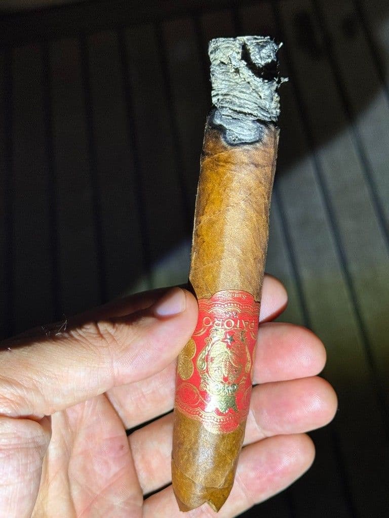 Patoro XO mid-smoke with uneven burn line and flaky ash