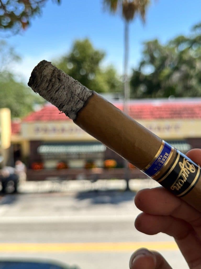 Byron Elegantes mid-smoke with stacked coin ash against a street backdrop